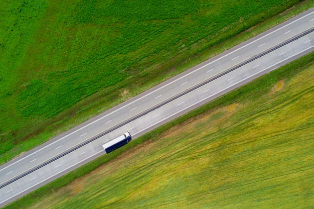 imagem de caminhão na estrada, com gramado verde nas laterais