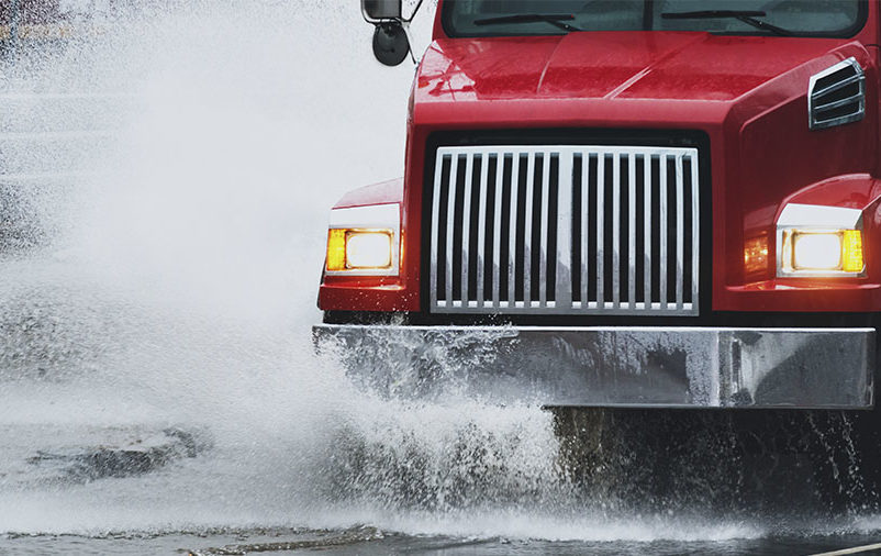 Um caminhão vermelho. Saiba como dirigir na chuva no artigo!